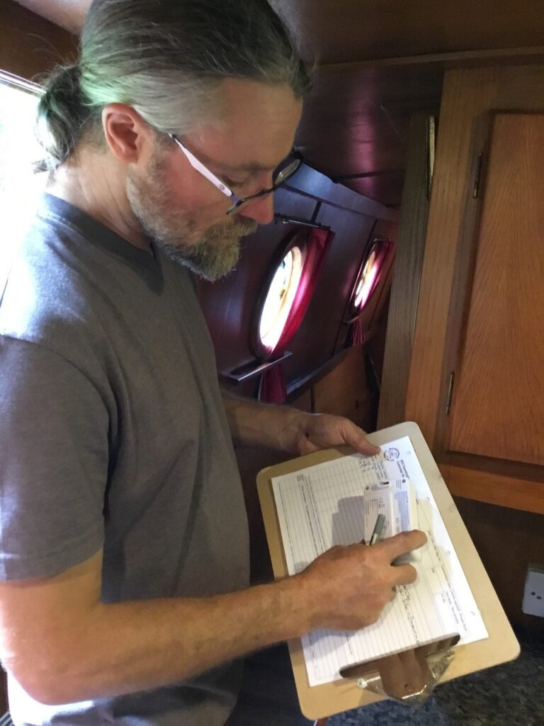 Man completing assessment form while inspecting a boat